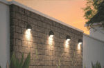 LED circular wall light illuminating exterior brick wall at sunset.