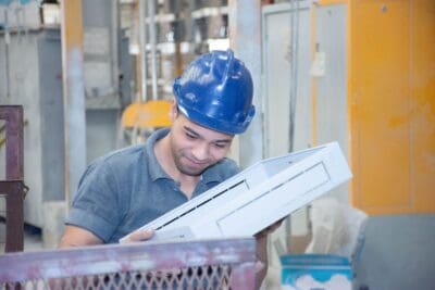 Werksmitarbeiter mit Schutzhelm prüft ein fertiges Produkt